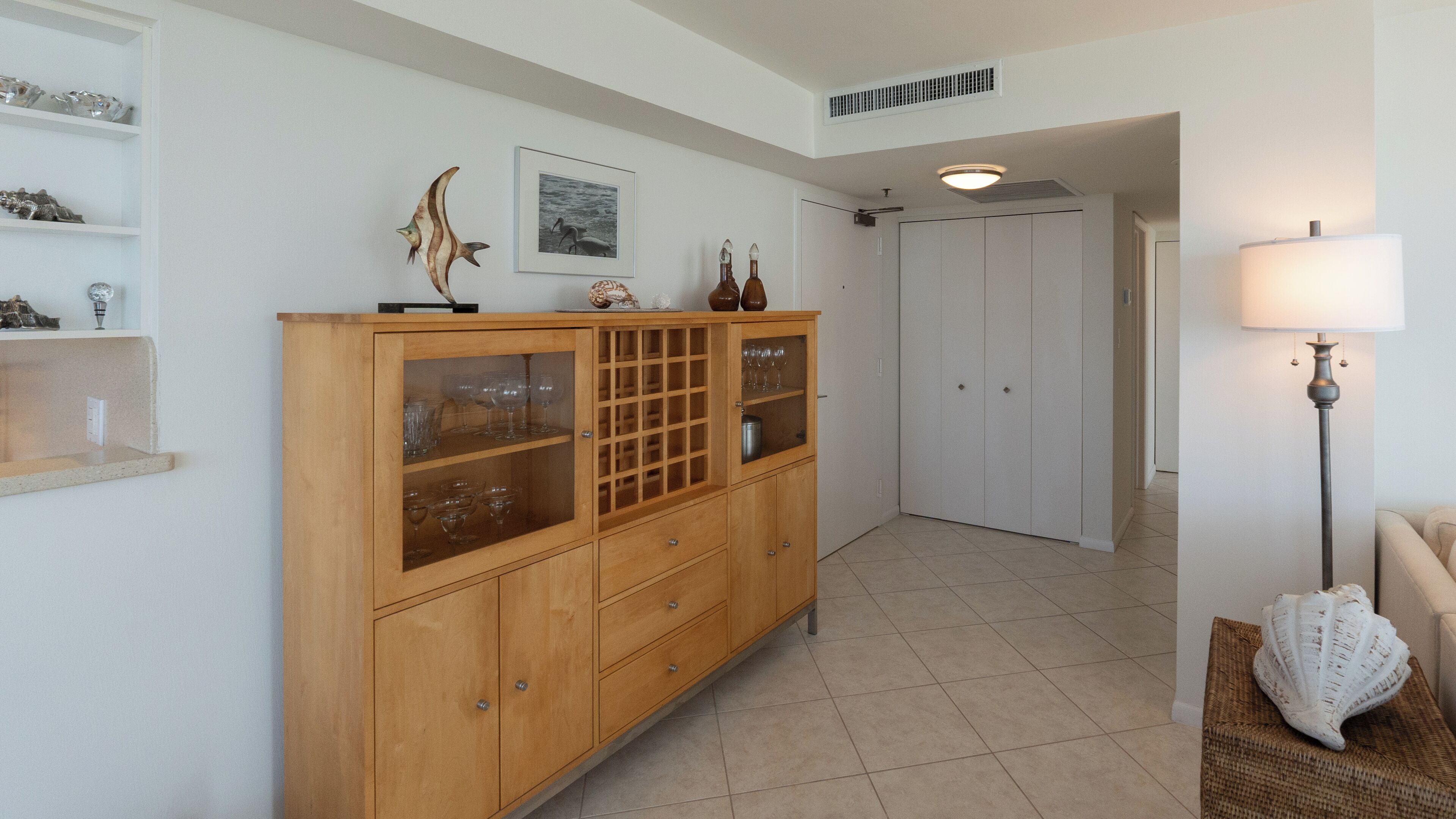 A hallway with a wooden cabinet, a framed picture, and a lamp.