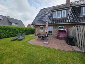 A house with a brick exterior, a tiled roof, a patio with a table and chairs, and a striped awning. - Torben´s Hüs - Torben´s Hüs, Borgsum (Borgsum)
