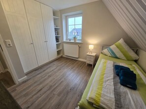 A bedroom with a bed, a nightstand, a window, and a wardrobe. - Torben´s Hüs - Torben´s Hüs, Borgsum (Borgsum)