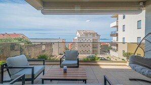 A balcony with two chairs, a table, and a view of buildings and the sea. - Awesome apartment in Tucepi with WiFi (Tucepi)