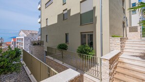 A modern apartment building with balconies, stone steps, and a view of the sea. - Awesome apartment in Tucepi with WiFi (Tucepi)