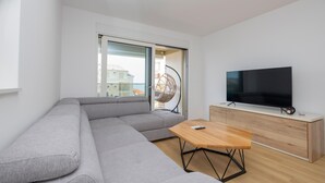 A modern living room with a grey sofa, a wooden coffee table, a TV on a wooden stand, and a wicker hanging chair. - Awesome apartment in Tucepi with WiFi (Tucepi)