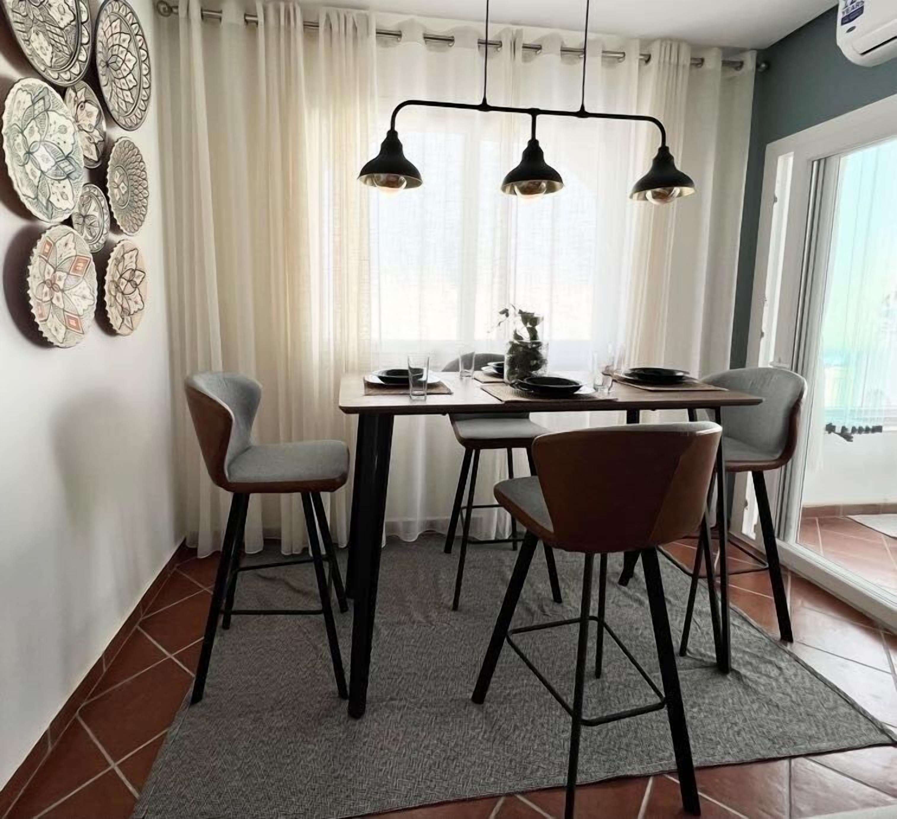 Een eetgedeelte met een tafel voor vier personen, een kroonluchter en decoratieve borden aan de muur.