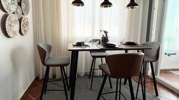 Een eetgedeelte met een tafel voor vier personen, een kroonluchter en decoratieve borden aan de muur.