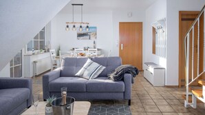 Un salon moderne avec un canapé gris, une table basse en bois et, au fond, un coin repas.
