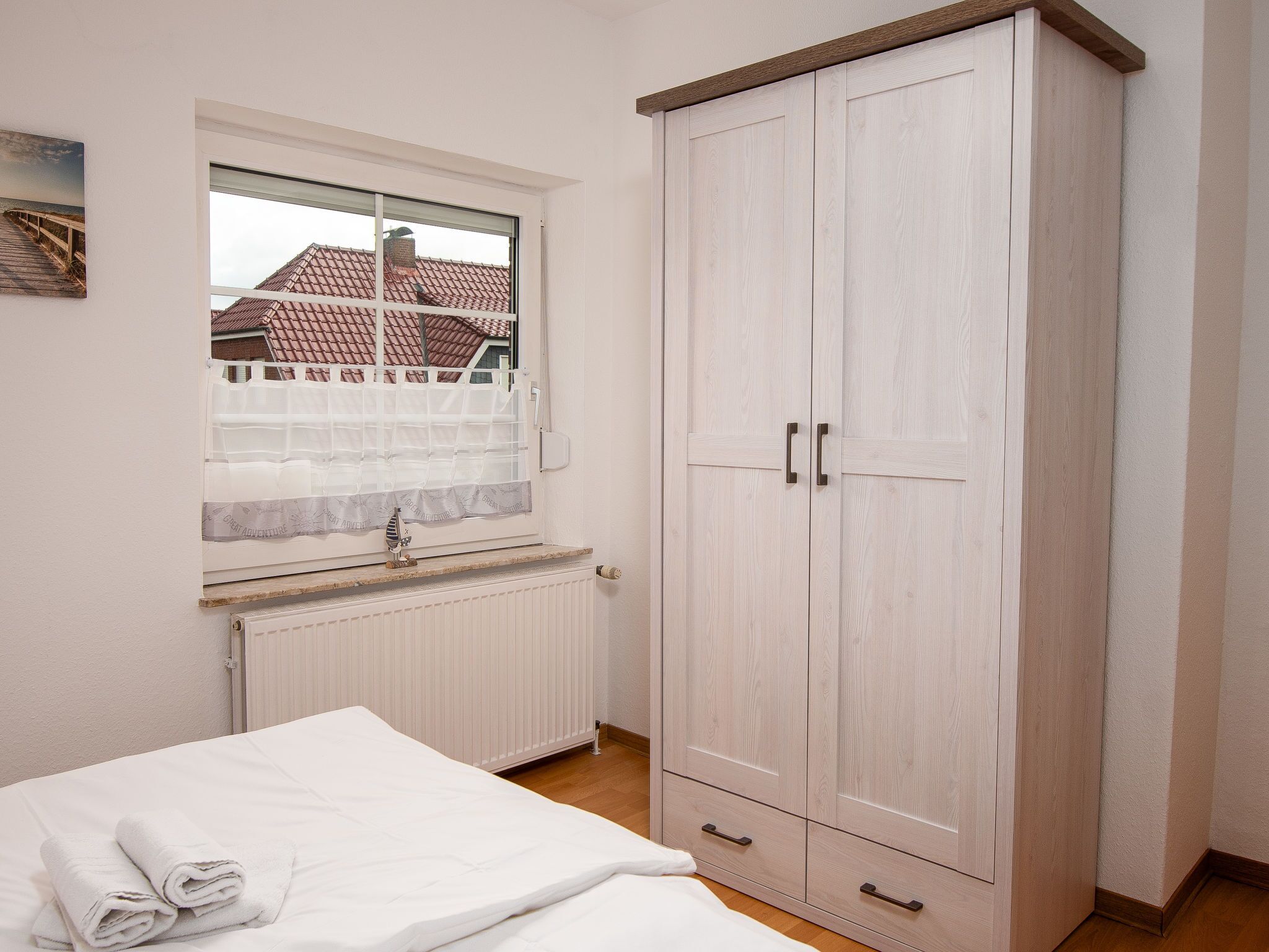 Une chambre à coucher avec un lit, une fenêtre donnant sur un immeuble, un radiateur et une armoire.