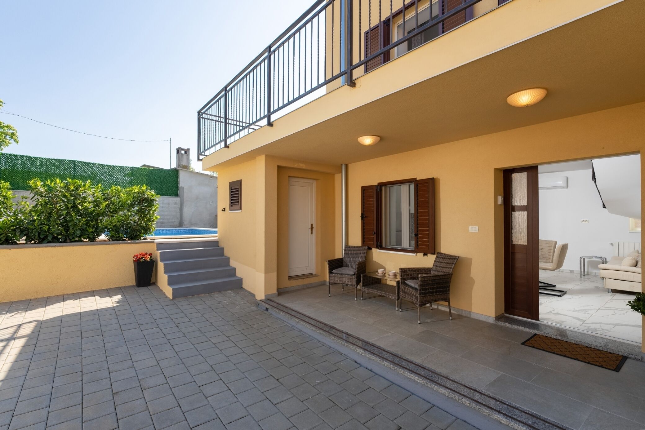 A two-story building with a balcony, outdoor seating area, and a staircase leading to the entrance.