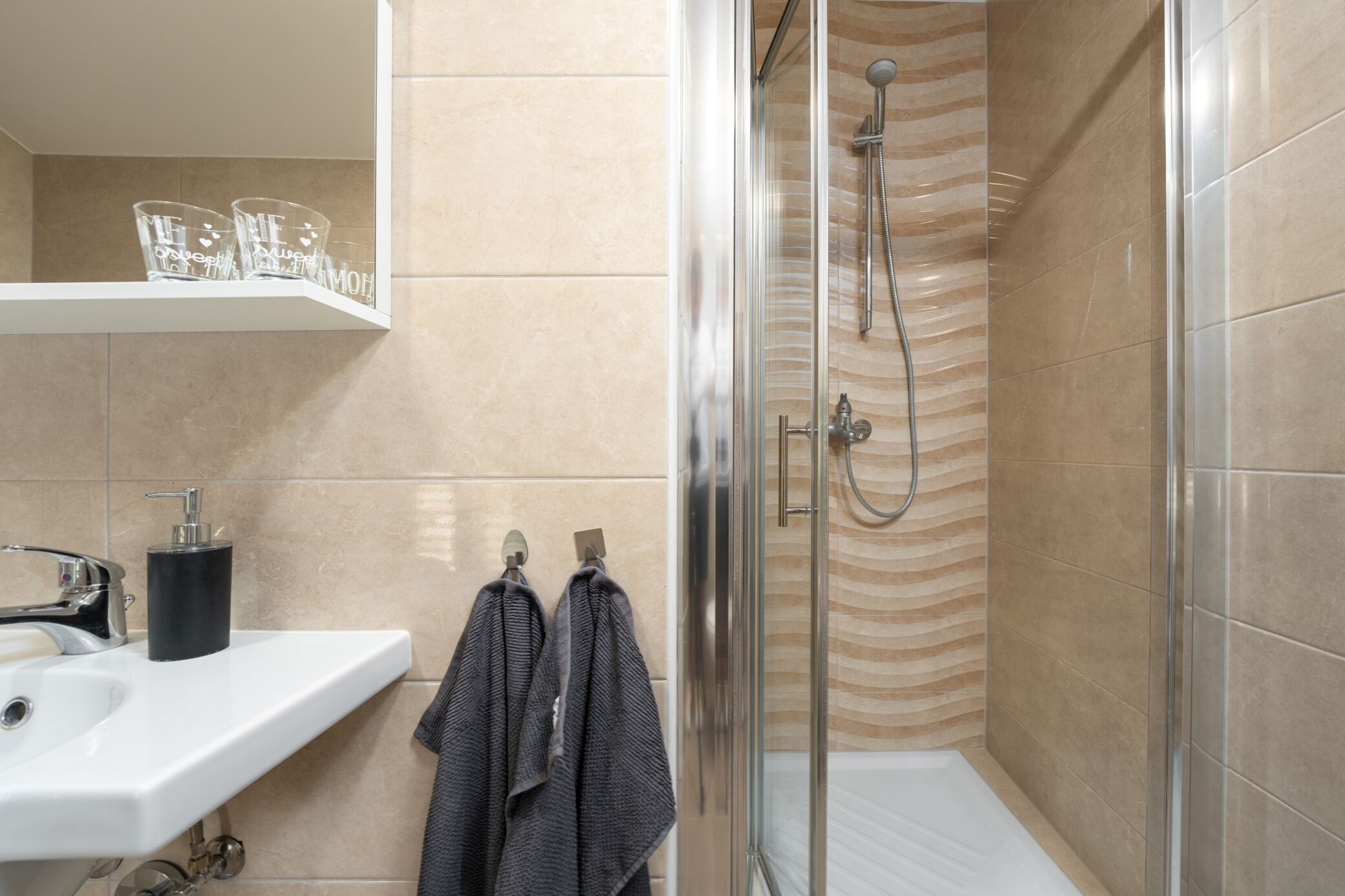 A bathroom with a shower, sink, and towel rack.
