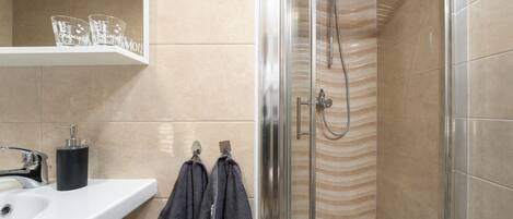 A bathroom with a shower, sink, and towel rack.
