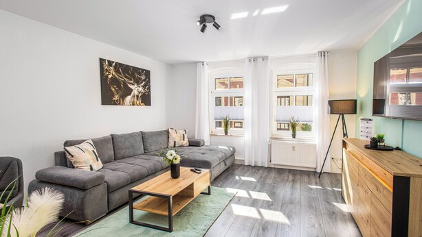 En moderne stue med en grå sofa, et træbord og en grøn måtte.