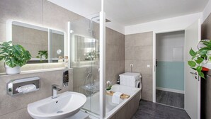 Et moderne badeværelse med et glasafskærmet brusebad, en stor vask og et toilet.