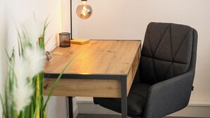 Et træskrivebord med en moderne lampe, en stol og en plante.