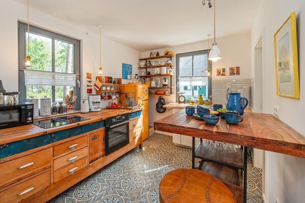 A kitchen with a wooden countertop, a built-in oven, and a coffee machine.