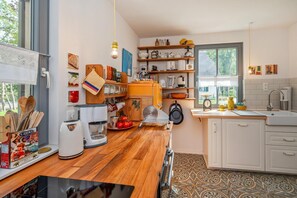 A kitchen with wooden countertops, a coffee maker, a kettle, and a window with a view of greenery. - Ferienhaus Auszeitfischer - Neu Errichtetes Ferienhaus in Ruhiger Wohngegend mit Parkplatz, Sauna (Zirchow)
