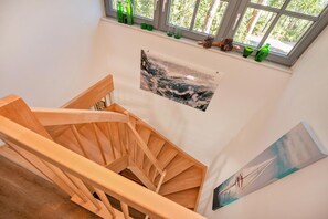 A wooden staircase with a view of a forest through a window.