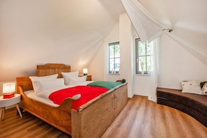 A room with a wooden bed, a bench, and a window with curtains.