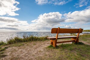 A wooden bench by a body of water with a clear sky.