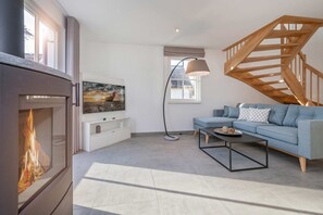 Una sala de estar moderna con chimenea, un sofá, una mesa de centro y una escalera.