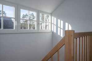 Una habitación con una escalera de madera y ventana con vistas a una zona residencial.
