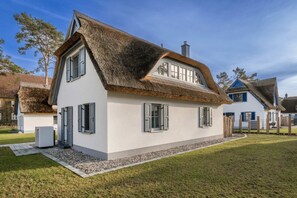 A white house with a thatched roof and a small attached structure.