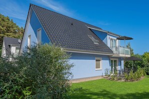 A two-story house with a sloped roof, a balcony, and a well-maintained lawn. - Ferienhaus Himmelblau OG - Entspannte Auszeit: Fewo in Loddin für 4 Gäste (Loddin)