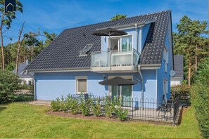 Uma casa de dois andares com varanda, antena parabólica e um pequeno jardim.