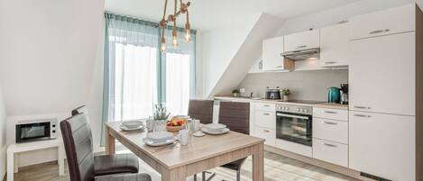 A modern kitchen with a dining area, featuring a wooden table, chairs, and a unique light fixture.