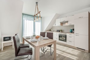 A modern kitchen with a dining area, featuring a wooden table, chairs, and a unique light fixture.