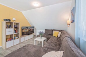 Ein Wohnzimmer mit Sofa, Couchtisch, Fernseher und Bücherregal.
