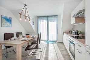 Una cocina moderna con horno empotrado, un comedor con mesa y sillas de madera, y un mapa en la pared.