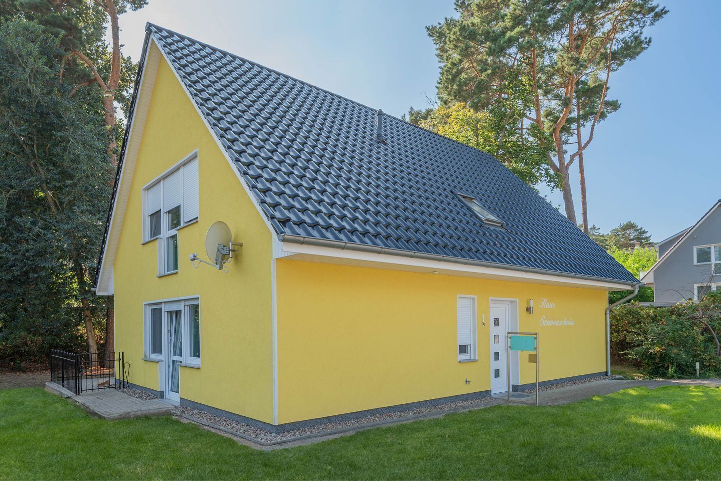 A yellow two-story house with a sloped roof, a satellite dish, and a small porch.