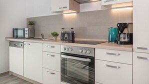 A modern kitchen with a dishwasher, oven, toaster, and coffee maker.