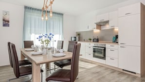 A modern kitchen with white cabinets, a built-in oven, and a coffee maker.