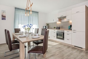 A modern kitchen with white cabinets, a built-in oven, and a coffee maker.