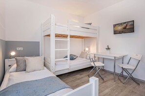 A bunk bed with a desk and chairs, a bedside table with a lamp, and a wall-mounted TV. - Ferienhaus Strandmöwe EG - Idyllisches Ferienparadies mit Sauna in Loddin (Loddin)