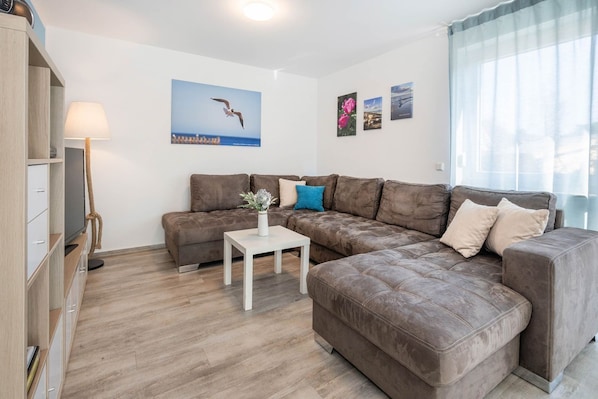 A modern living room with a sectional sofa, a small white table, and a television.