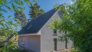 Moderni, kaksikerroksinen talo, jossa on kalteva katto, suuret ikkunat ja hyvin hoidettu nurmikko.