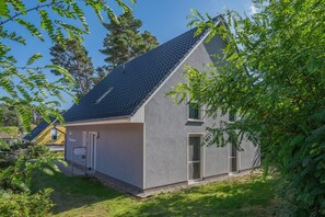 Une maison moderne à deux étages, dotée d’un toit en pente, de grandes fenêtres et d’une pelouse bien entretenue.