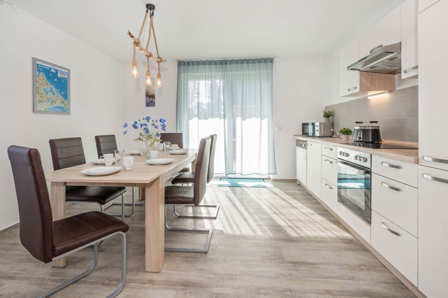 A modern kitchen with white cabinets, stainless steel appliances, and a dining area with a wooden table and chairs.