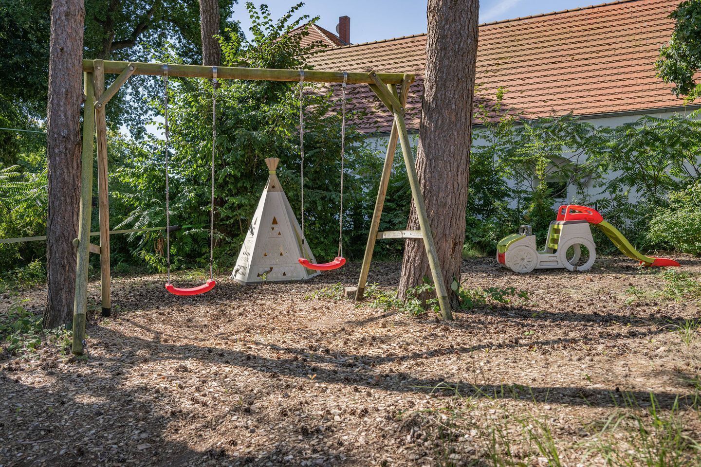 Une aire de jeux avec des balançoires, un toboggan et une structure d’escalade.