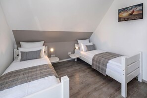 Une chambre avec deux lits, une table de chevet et une commode, ainsi qu’un tableau accroché au mur.