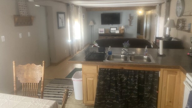 Een compacte keuken met een centraal eiland, een eethoek met een stoel en een zichtbare prullenbak.
