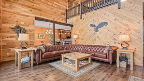 Uma sala de estar acolhedora com um sofá de couro, mesa de centro de madeira e uma parede de madeira com um mural de uma águia.
