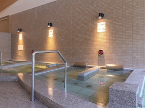Un espace de bains public doté de murs carrelés, d’un affichage numérique de la température et d’une main courante en métal.