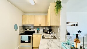 Una cocina moderna con armarios de madera, estufa de acero inoxidable, microondas y un lavamanos.