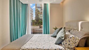A bedroom with a bed, curtains, a view of buildings, and a window. - Canal Side Luxury 1 Bed Chelsea (Greater London)