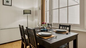Una mesa de comedor lista con platos, vasos y un florero.