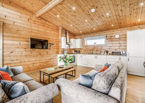 A log cabin interior with a living room, kitchen, and dining area.