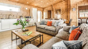 A log cabin interior with a living area, sofa, coffee table, and kitchen.
