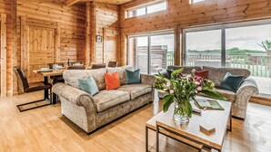 A wooden interior with a sofa, coffee table, and dining area.